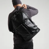 Большой кожаный рюкзак черный, на плече мужчины