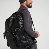 Большой кожаный рюкзак черный, на плече мужчины