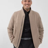 Мужчина в бомбере на молнии серо-бежевого цвета, вид спереди