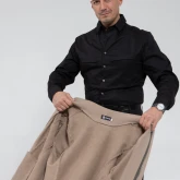 Мужчина держит бомбер на молнии серо-бежевого цвета, вид изнутри