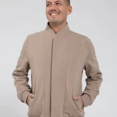 Мужчина в бомбере на молнии серо-бежевого цвета, вид спереди