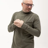 Асимметричная зеленая футболка с длинным рукавом, модель показывает рукав спереди