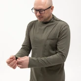 Асимметричная зеленая футболка с длинным рукавом, модель сбоку поправляет манжет